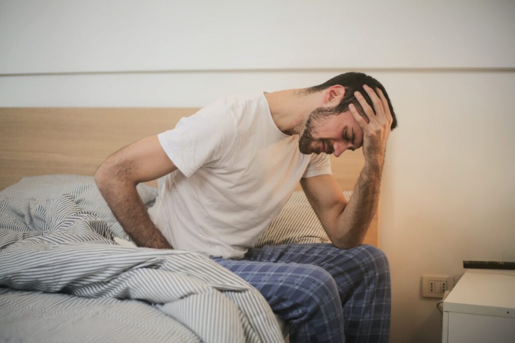 Man sitting in bed, not feeling well.